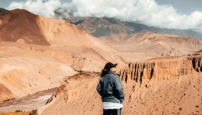 man in black jacket standing on brown rock formation during daytime